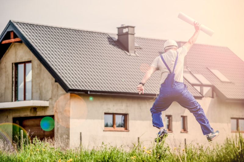 Builder jumping in front of a newly finished house.